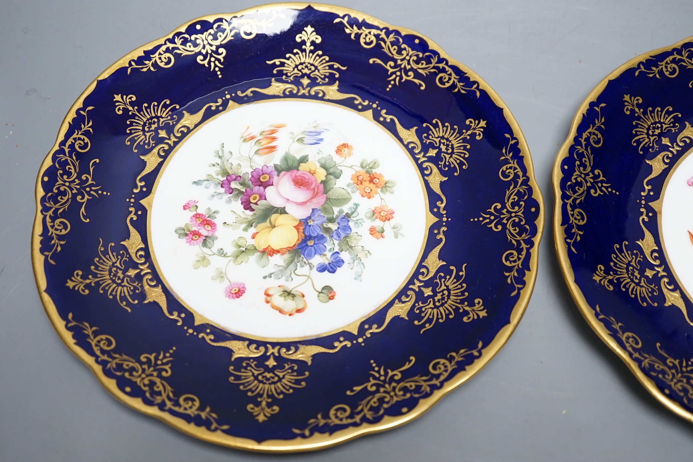 A pair of Coalport floral plates with cobalt blue borders having raised and flat gilding, both by Frank Howard, signed F. Howard, made for Waring and Gillows, Crown England mark